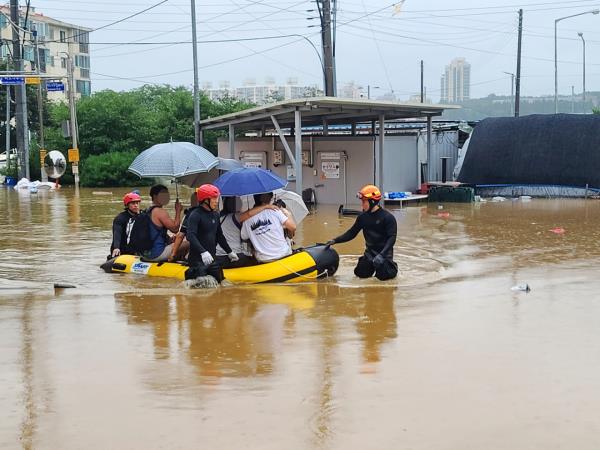 Rescuers evacuate residents on a flooded street in the central city of Gongju on July 15, 2023, in this photo provided by a reader. (Yonhap)